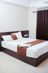 two beds in a hotel room with white and brown at krishna suites guruvayur in Guruvāyūr