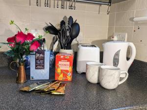 a counter top with cups and utensils on it at Sherlock's Moray House -Idea long stay for contractors & family Two bedroom mid terrace 3 beds 2 sofa beds Sleep 5 Working facility Free WiFi TV & private parking Enclose rear garden dog friendly Sainsbury's & takeaway pubs in walking distance in Church Gresley
