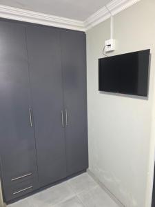 a room with grey cabinets and a tv on the wall at The Good Samaritan 1 in eMalahleni