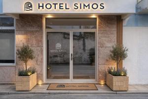 a hotel entrance with a glass door and two plants at Hotel Simos in Mitika