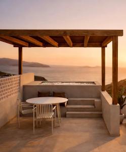 a patio with a table and chairs and the ocean at Astypalaia Hotel Palace in Astypalaia