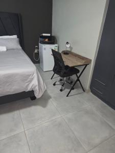 a bedroom with a desk and a bed and a chair at The Good Samaritan 1 in eMalahleni