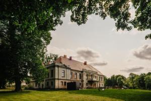 an old house in a field with a tree at Folwark Wielka Wieś in Główczyce