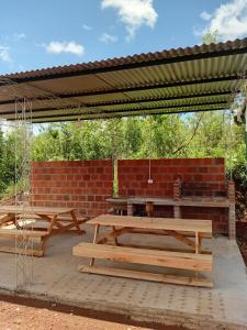 two picnic tables under a pavilion with a brick wall at CABAÑAS Gaucho RIVERO in El Soberbio +8 photos