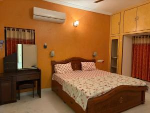 a bedroom with a bed and a dresser and a television at Naidu Villa in Secunderabad