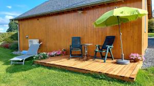 a wooden deck with two chairs and an umbrella at Chez Théo in Trois-Ponts +10 photos