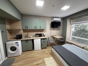 a bedroom with a bed and a kitchen with a washing machine at Nõma studio in Varna City