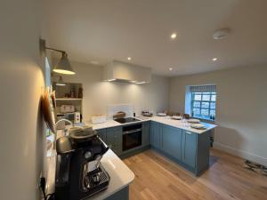 a kitchen with blue cabinets and white counter tops at Gilchrist Square in Dornoch