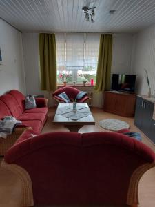 a living room with red couches and a coffee table at Ferienhaus Hanna in Apen