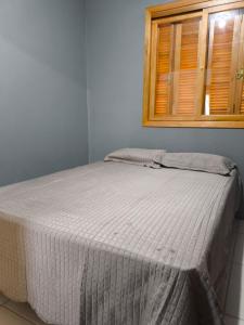 a small bed in a room with a window at Casa com dois quartos cama de casal e vista panorâmica próximo a Gramado Serra Gaúcha in Igrejinha