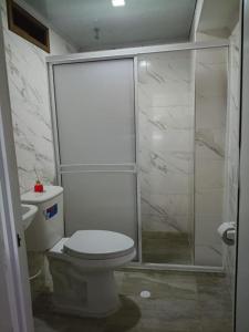 a white bathroom with a toilet and a shower at KOKOA GARDEN INN in San Vicente de Chucurí
