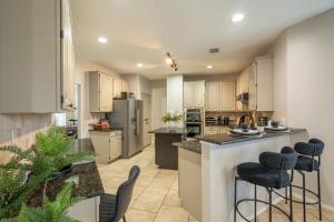 a large kitchen with white cabinets and bar stools at Stylish Oasis Modern Living in Allen