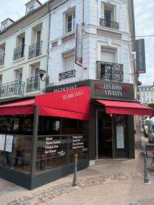 a store front of a building with red awnings at Les Bons Vivants - L'appartement in Trouville-sur-Mer