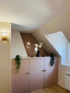 a attic room with a cabinet with flowers on it at Les Bons Vivants - L'appartement in Trouville-sur-Mer