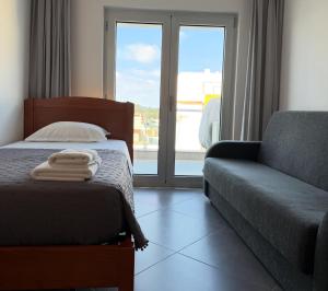 a bedroom with a bed and a couch and a window at Vela Terrace in Monte Gordo +2 photos