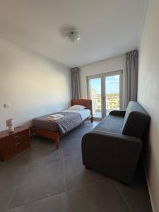 a room with a bed and a couch and a window at Vela Terrace in Monte Gordo