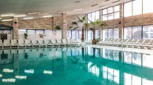 a swimming pool with white chairs in a building at Old house by the stream in Donja Stubica