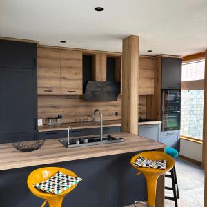 a kitchen with wooden cabinets and two yellow bar stools at Loft Chalet Bansko in Bansko