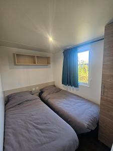 two beds in a small room with a window at Chalet First Stage - Renesse in Renesse