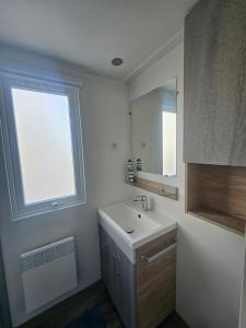 a white bathroom with a sink and a window at Chalet First Stage - Renesse in Renesse +25 photos