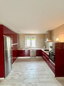 a kitchen with red cabinets and stainless steel appliances at Hispalis villa de Espartinas in Espartinas
