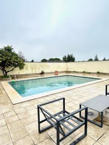 a swimming pool with two chairs and a bench at Hispalis villa de Espartinas in Espartinas