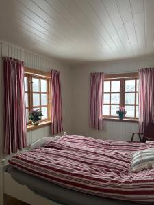 a large bed in a bedroom with two windows at Familievennlig fritidsbolig i hjertet av Flå, perfekt for besøk i Bjørneparken in Flå