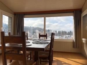 a dining room with a table and a large window at Chalet Belfahy in Belfahy