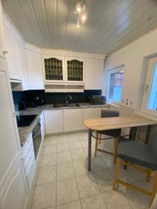 a kitchen with white cabinets and a wooden table at Möwennest in Barsbek +5 photos