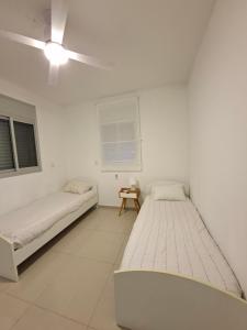 two beds in a white room with a ceiling fan at Shave Tsion Apartment in the center Ashdod in Ashdod