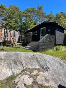 a black house with a porch and a playground at Peaceful seaside cabin with guest house - large private outdoor areas and boat available on request in Eigebrekk