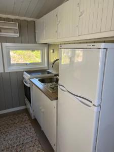 a kitchen with a white refrigerator and a sink at Peaceful seaside cabin with guest house - large private outdoor areas and boat available on request in Eigebrekk +22 photos