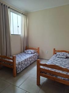 two beds in a room with a window at Apartamento da Adriana in Itajubá