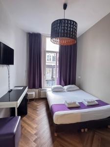 a bedroom with a bed and a desk and a chandelier at Hotel Bellington in Amsterdam