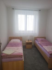 two twin beds in a room with a window at Komárov Apartment 2 in Komárov +1 photo