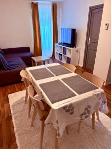 a table and chairs in a living room with a tv at Le Cosy Home in Guebwiller +7 photos
