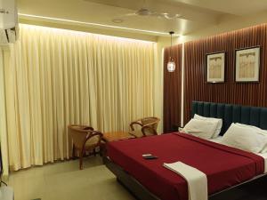 a bedroom with a bed with a red blanket and chairs at Hotel Vaishnavi in Solapur