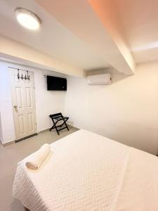 a bedroom with a white bed and a tv at Mosaico Cartagena Hotel in Cartagena de Indias