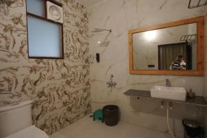 a man taking a picture of a bathroom with a mirror at Corbett Valley View in Tota Ām