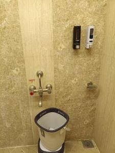 a toilet in a bathroom with a phone on the wall at Hotel Vaishnavi in Solapur +115 photos