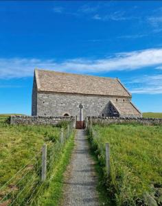 an old stone church in a field with a fence at An Gearasdan in Eoropie