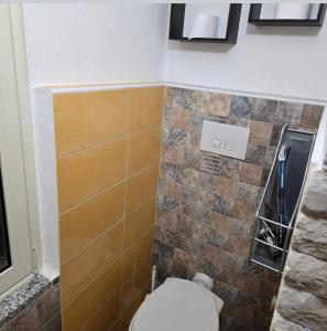 a bathroom with a toilet and a tiled wall at La Nicchia Del Borgo in Badolato