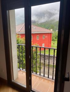 a window with a view of a red house at La Terraza de Sovega in Arenas de Cabrales +3 photos