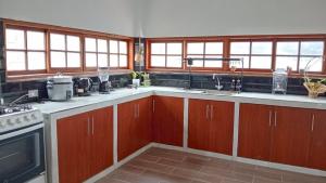 a kitchen with wooden cabinets and sinks and windows at Casa Blanca Andina in Cajamarca