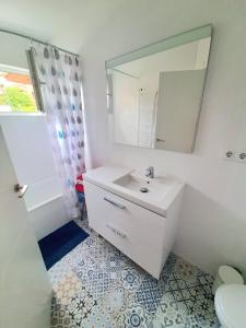 a white bathroom with a sink and a mirror at Acogedor apartamento de 2 habitaciones, parking & conford in El Astillero +12 photos