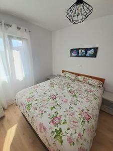 a bedroom with a bed with a floral bedspread at Acogedor apartamento de 2 habitaciones, parking & conford in El Astillero