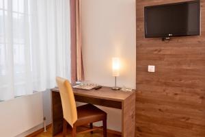 a desk with a chair and a television on a wall at Lemon Living Self-Check-in in Ottensheim