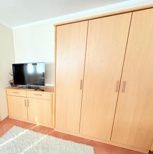 a room with two large wooden cabinets with a flat screen tv at Fewo Lavendel - mit Dachterrasse, Hund ist willkommen in Mariendorf