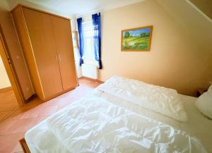 a bedroom with a white bed and a cabinet at Fewo Lavendel - mit Dachterrasse, Hund ist willkommen in Mariendorf