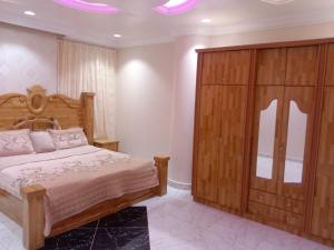 ein Schlafzimmer mit einem Bett und einem großen Holzschrank in der Unterkunft أبراج وطني in Al Bahah